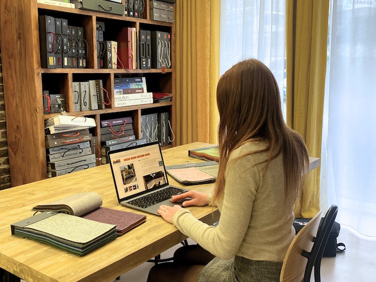 Une experte assise à un bureau avec des échantillons de tissus pour un rendez-vous en visio.